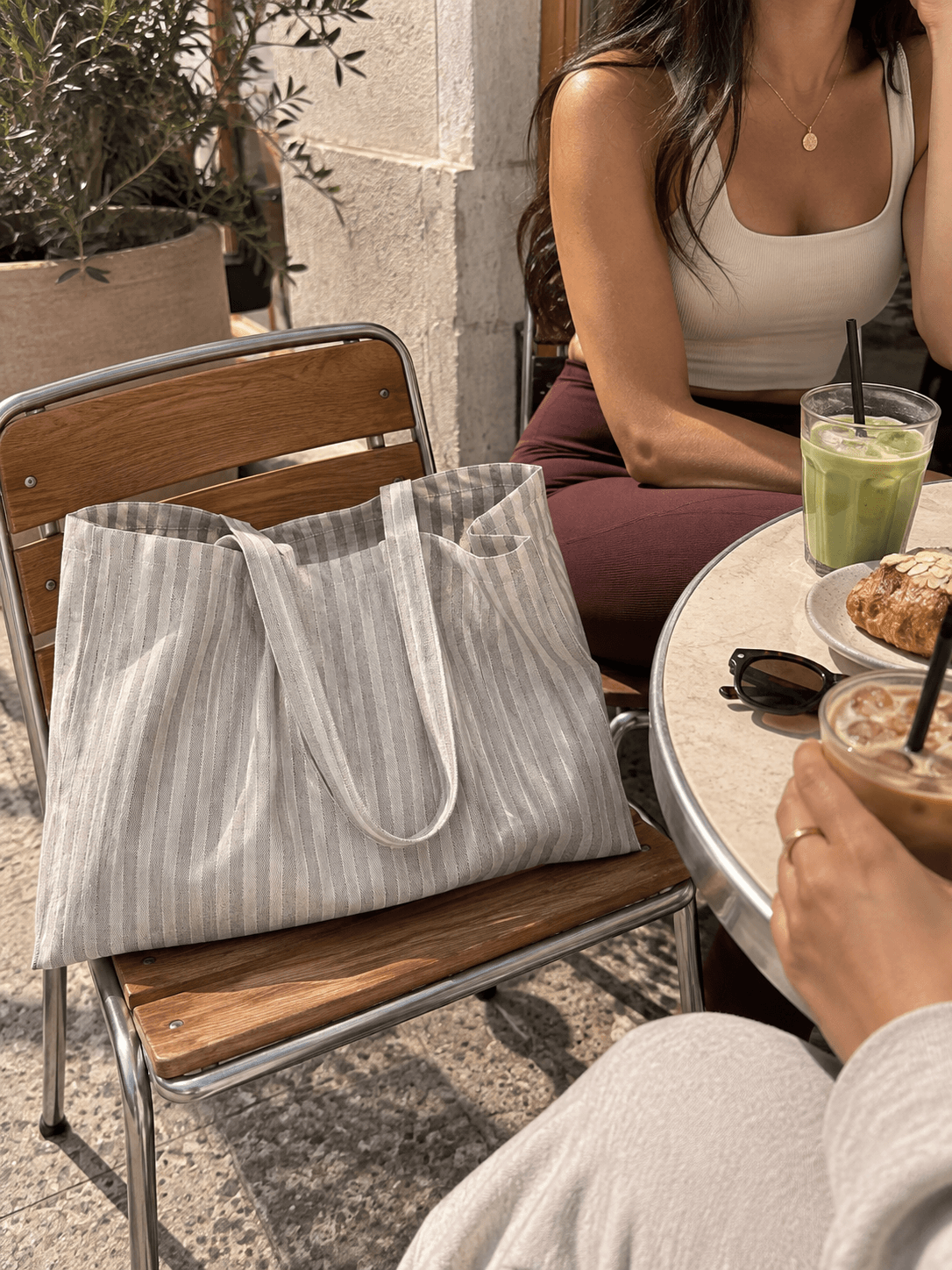 Striped tote on a café chair beside iced drinks.