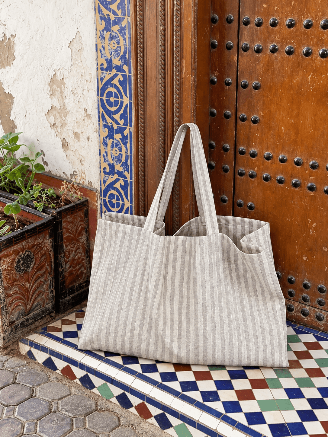Striped tote on a tiled doorstep against a carved wooden door.